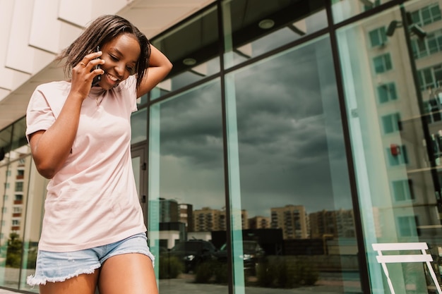 Foto mujer afroamericana sostenga el teléfono de la mano navegando por internet chateando amigos colega