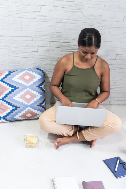 Mujer afroamericana en sus 3039 trabajando en su computadora portátil en casa sentada en el suelo