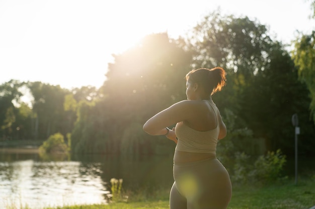 Mujer afroamericana de tamaño plus estirándose en el parque en un día de verano