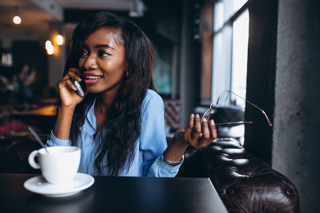 Mujer afroamericana con teléfono en un café