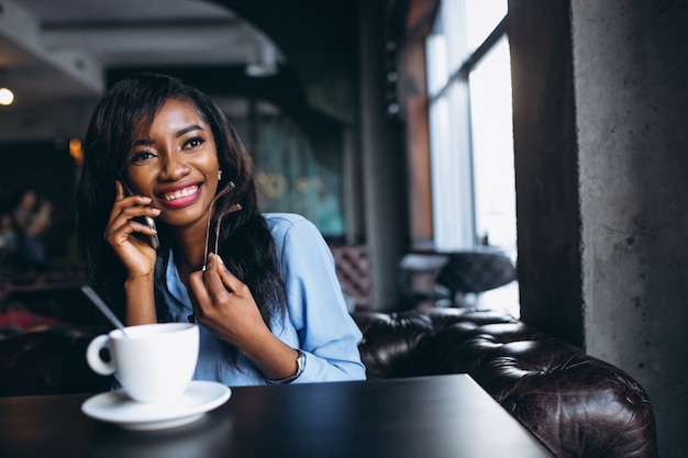 Mujer afroamericana con teléfono en un café