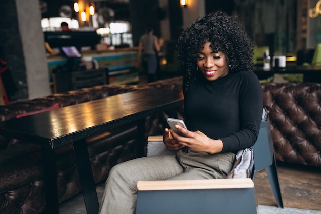 Mujer afroamericana con teléfono en café