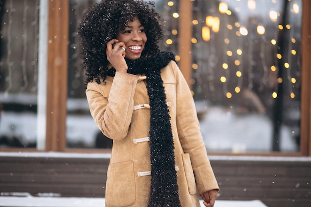 Mujer afroamericana con teléfono en invierno