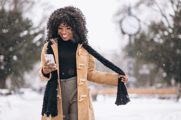 Mujer afroamericana con teléfono en invierno