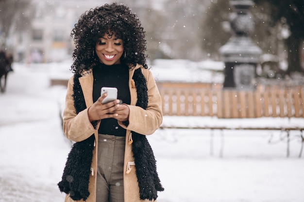 Mujer afroamericana con teléfono en invierno