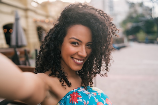 Mujer afroamericana tomando un selfie en la ciudad.