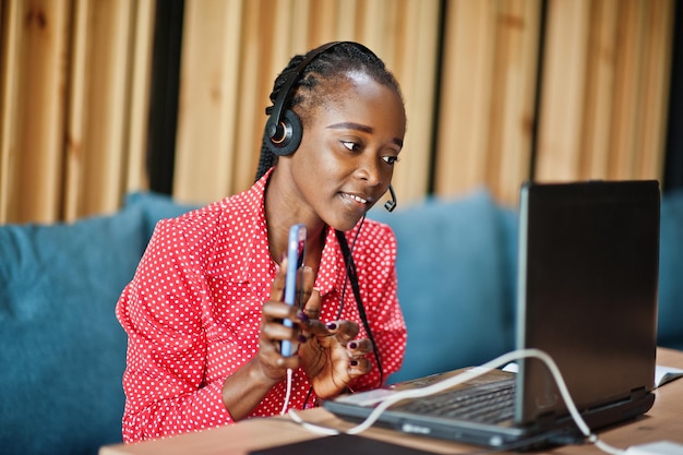 Mujer afroamericana trabaja en un operador de centro de llamadas y agente de servicio al cliente con auriculares de micrófono que trabajan en una computadora portátil