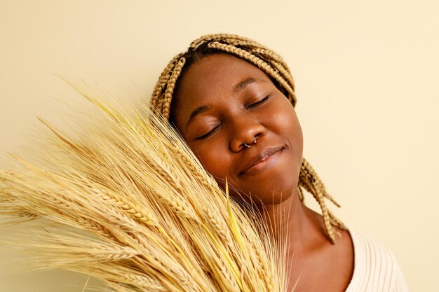 mujer afroamericana con trenzas y plantas de trigo