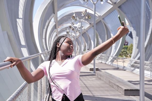 Mujer afroamericana con trenzas tomándose un selfie con su smartphone