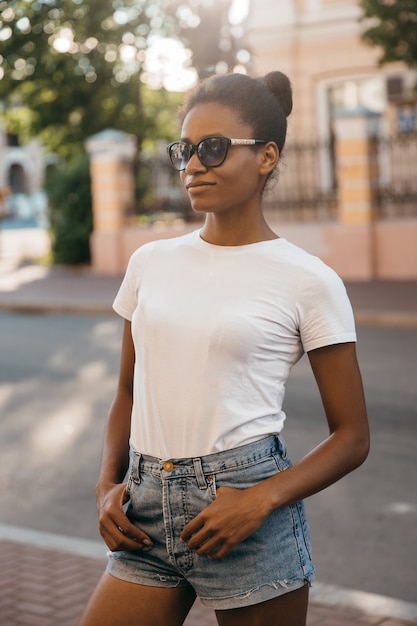 Mujer afroamericana urbana caminando por la plaza de la calle de la ciudad al atardecer