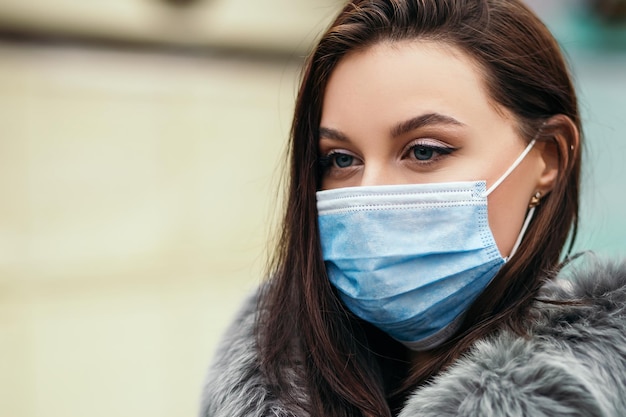 La mujer se para afuera use una máscara desechable de cara azul para protegerse contra virus o infecciones