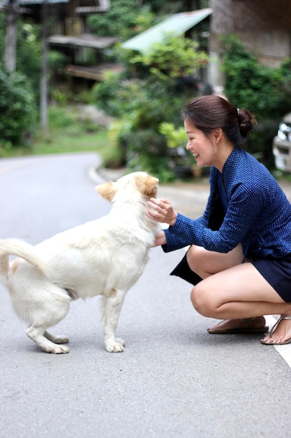 Mujer agachada por el perro en la carretera