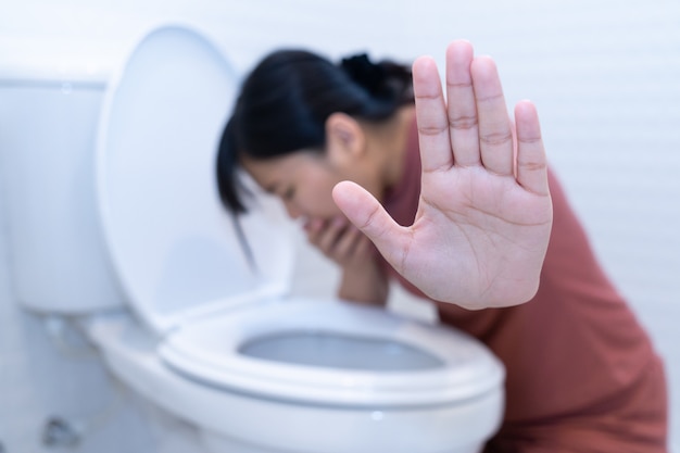 Foto mujer agarra la mano y vomita en el baño.