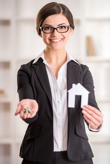 La mujer del agente inmobiliario está mostrando el hogar para la venta firma y las llaves.