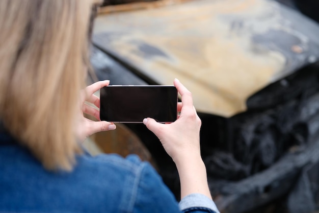 Mujer agente de seguros fotografía coche quemado en smartphone