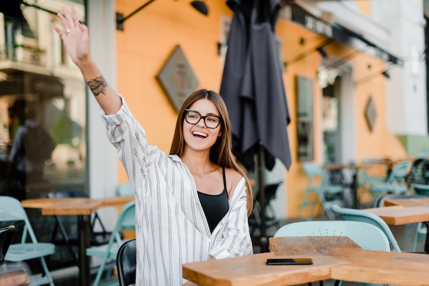 Foto mujer agitando la mano en la cafetería