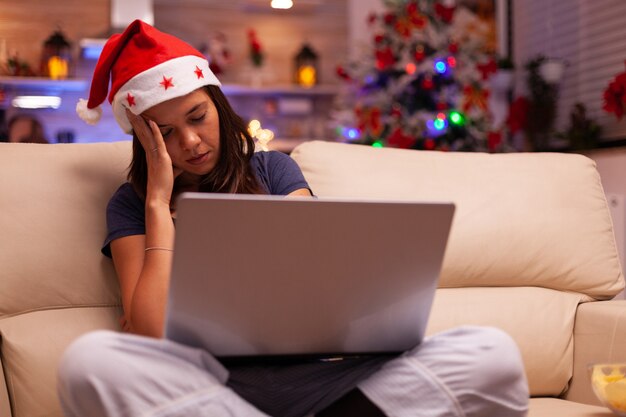 Mujer agotada cansada durmiendo en el sofá en la cocina decorada de Navidad