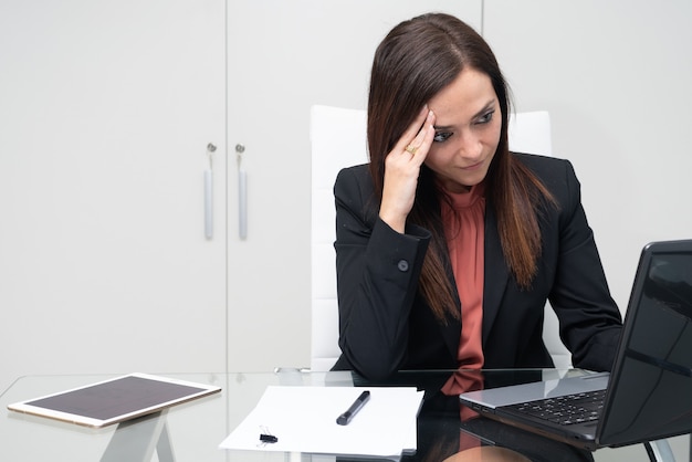 Mujer agotada por el trabajo en su oficina frente a la computadora portátil - enfoque selectivo