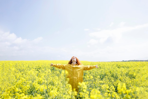 Mujer agradecida siendo feliz por un día soleado de verano en un campo de hermosas flores de colza