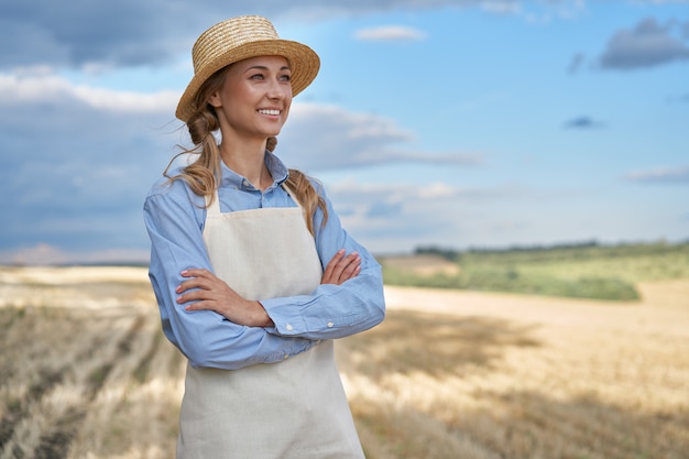 Mujer agricultor sombrero de paja delantal de pie tierras de cultivo