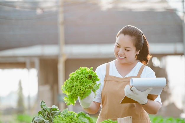 Mujer agricultora asiática que muestra vegetales de calidad en una granja hidropónica de vegetales orgánicos. concepto de plantación.