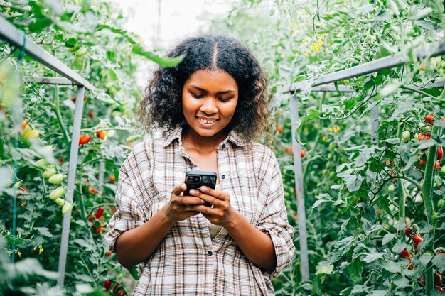 Mujer agricultora en el invernadero hablando por teléfono