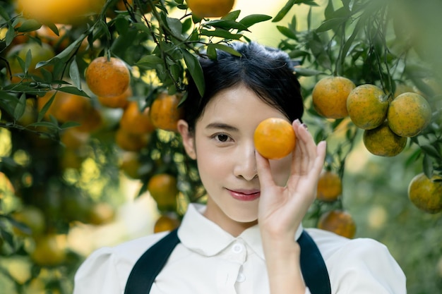 Mujer agricultora recogiendo cuidadosamente naranja madura en el huerto