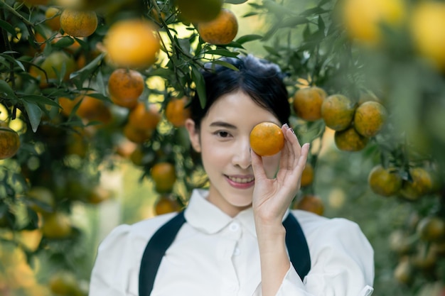 Mujer agricultora recogiendo cuidadosamente naranja madura en el huerto