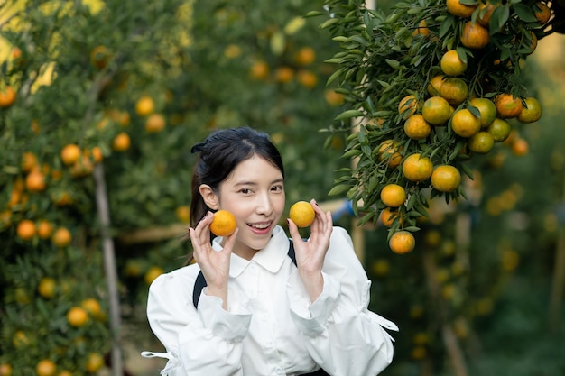 Mujer agricultora recogiendo cuidadosamente naranja madura en el huerto