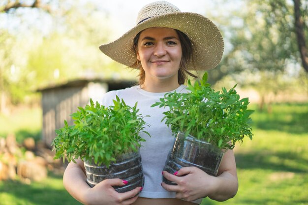 Mujer agrónoma sosteniendo plántulas en macetas Plántulas tempranas cultivadas a partir de semillas en cajas en casa