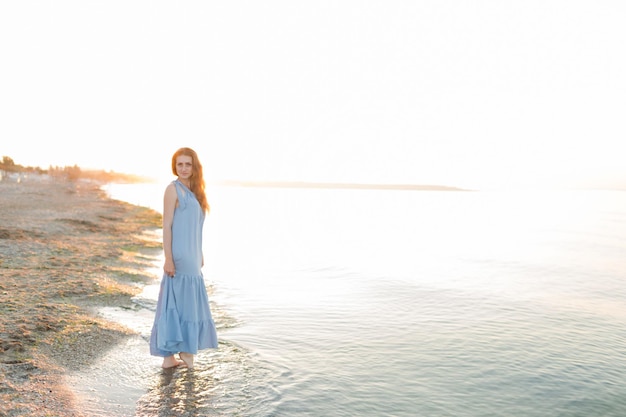 Una mujer se para en el agua frente a una puesta de sol.