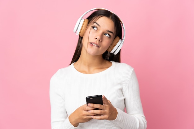 Mujer aislada en azul escuchando música con un móvil y pensando