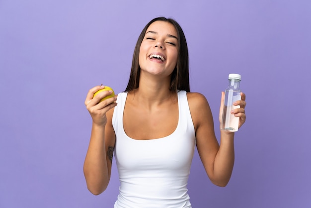 mujer aislada en morado con una manzana y con una botella de agua