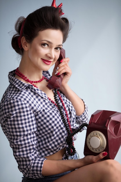 Mujer al estilo de los años cincuenta Hermosa chica retro hablando por un teléfono antiguo