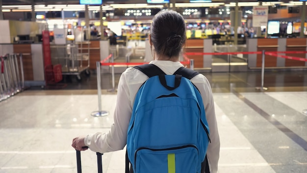 La mujer va al mostrador de registro en la vista posterior de la terminal del aeropuerto