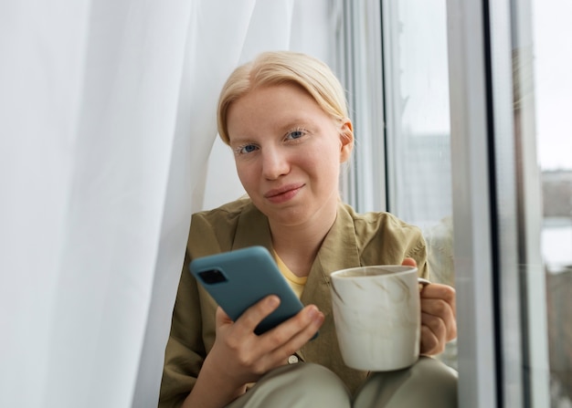 Foto mujer albina de tiro medio con teléfono inteligente