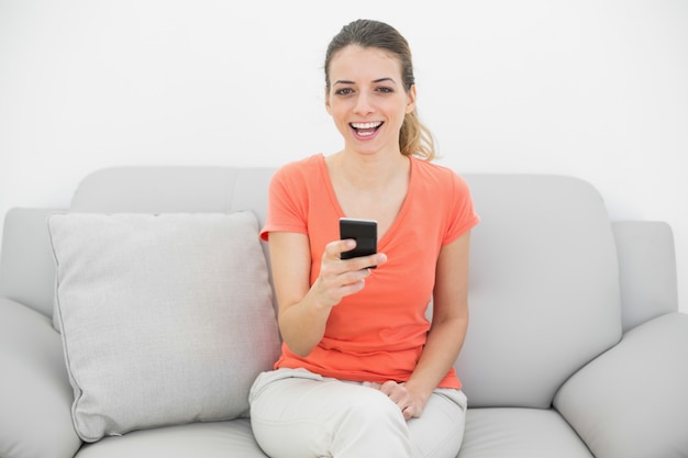 Mujer alegre alegre riendo sosteniendo su teléfono inteligente