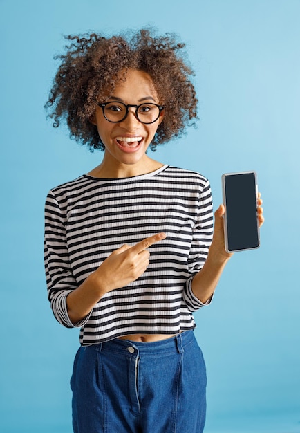 Mujer alegre apuntando al smartphone en estudio