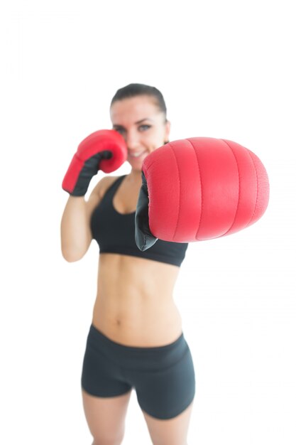 Mujer alegre atractiva que lleva guantes de boxeo rojos