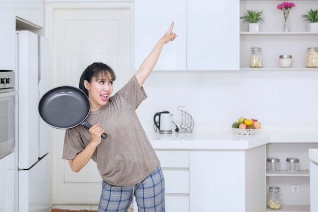 Mujer alegre bailando con una sartén