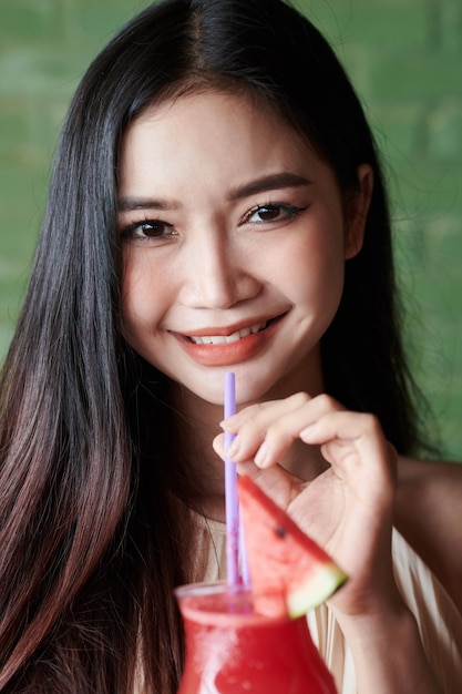 Mujer alegre bebiendo batido de sandía