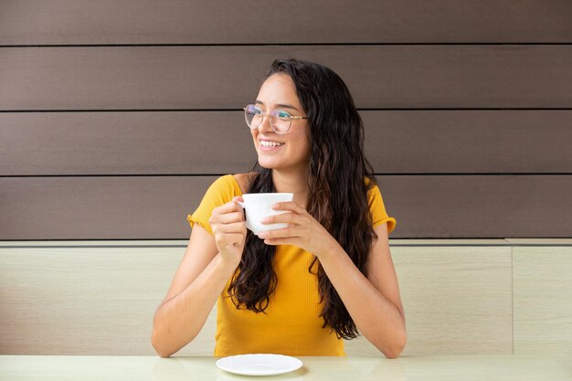 Mujer alegre bebiendo café en la cafetería