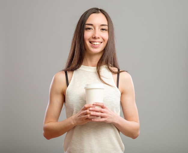 Mujer alegre bebiendo café de la mañana aislado sobre fondo gris