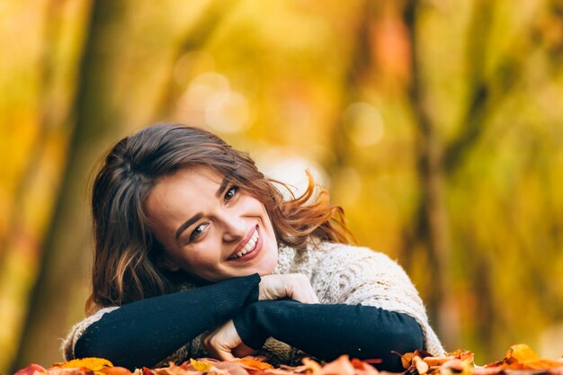 Mujer alegre con la cabeza inclinada hacia el lado sonríe paisaje otoñal