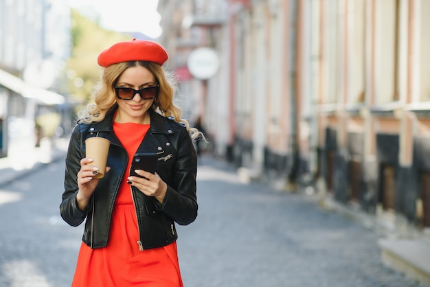 Mujer alegre en la calle bebiendo café por la mañana a la luz del sol