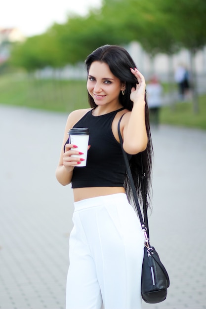 Mujer alegre en la calle bebiendo café de la mañana en el sol