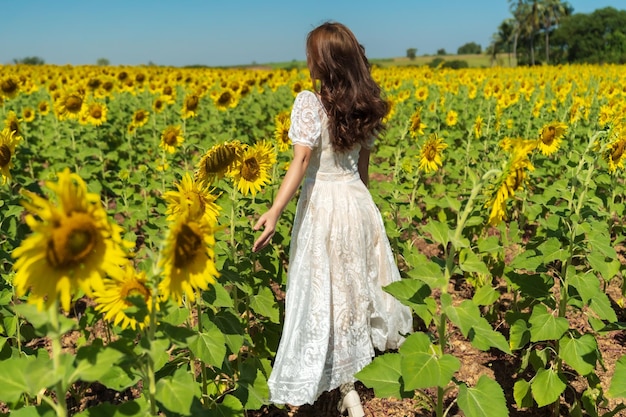 Mujer alegre caminando y disfrutando con campo de girasol