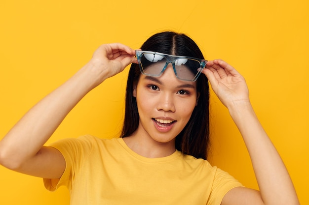 Mujer alegre con camiseta amarilla y gafas elegantes posando a la moda