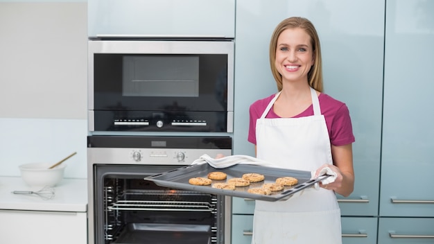 Mujer alegre casual con bandeja de horno con galletas