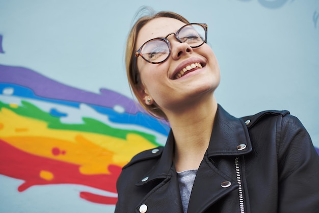 Mujer alegre chaqueta de cuero divertidas emociones gafas y graffiti multicolor